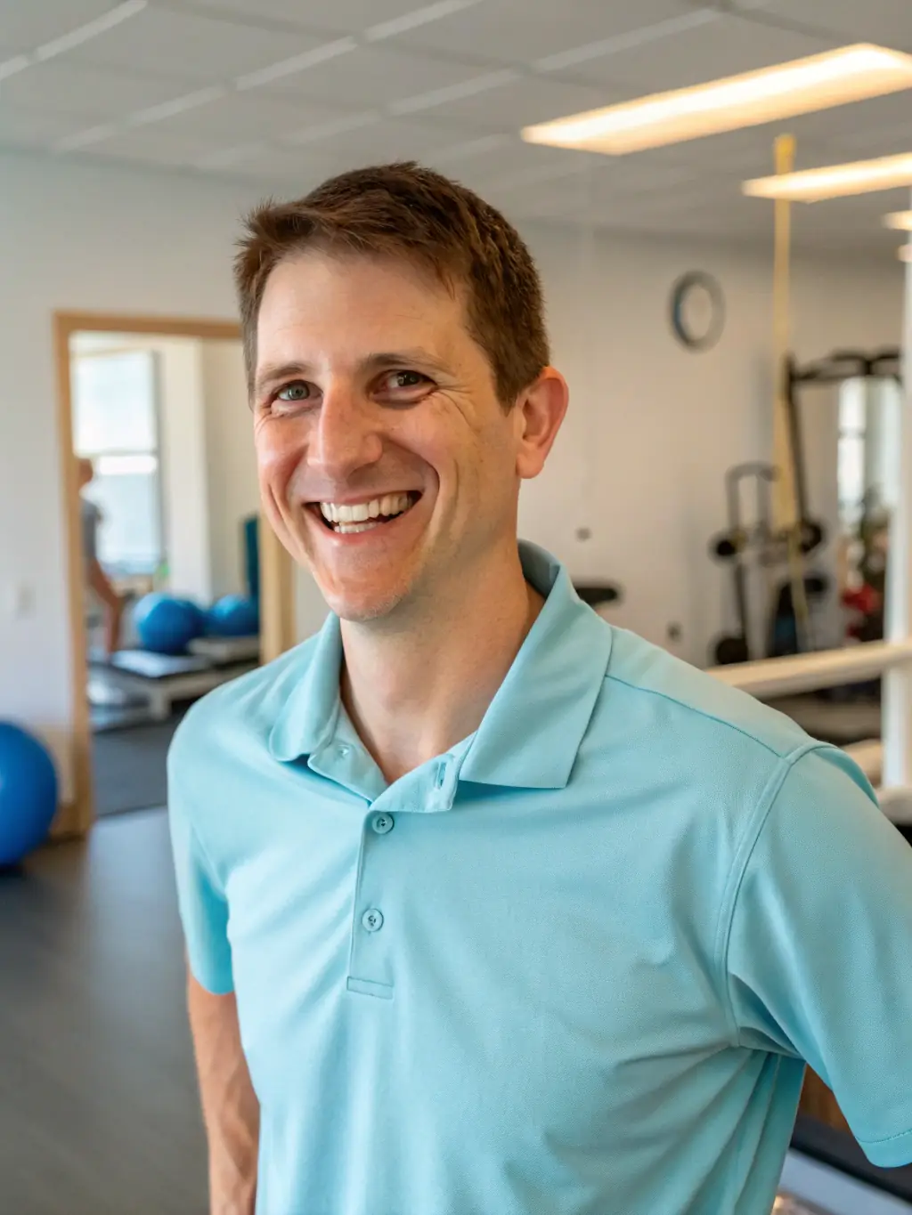 A professional headshot of a friendly and competent physical therapist in a modern rehabilitation clinic, smiling confidently.